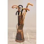 A collection of sixteen assorted walking sticks and canes to a brass and copper oxidised swing