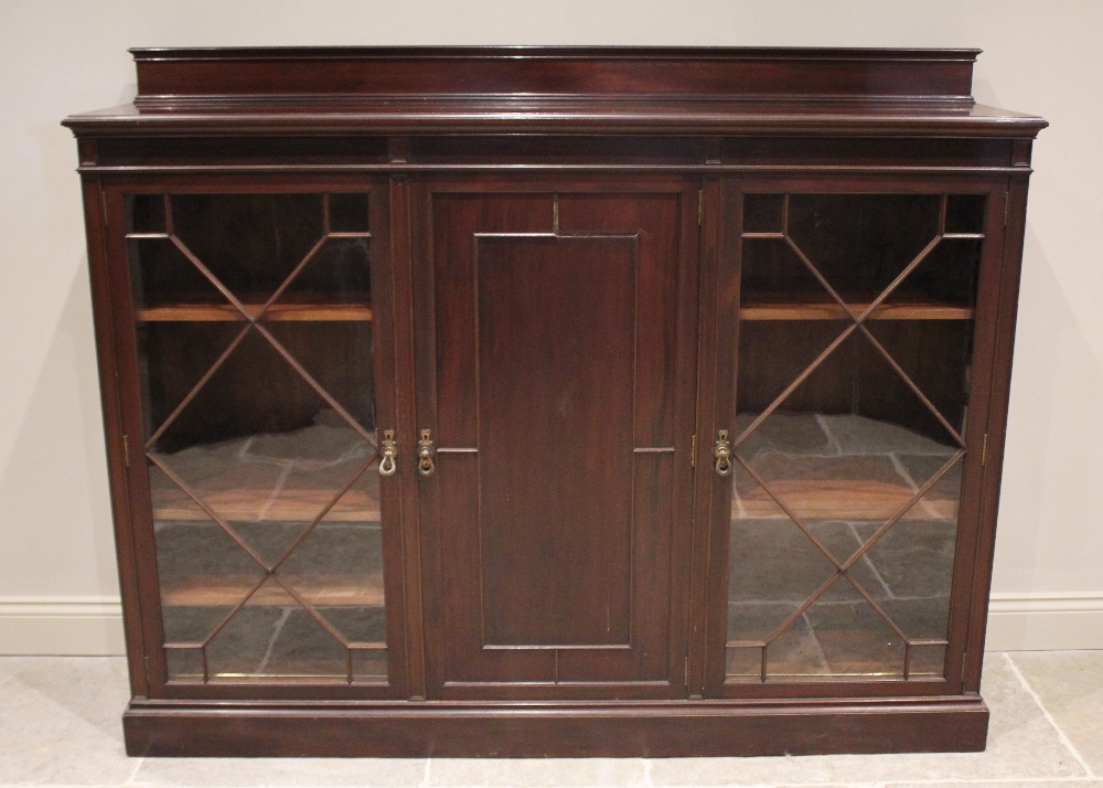 An early 20th century glazed mahogany bookcase, by Waring and Gillow, the central cupboard door