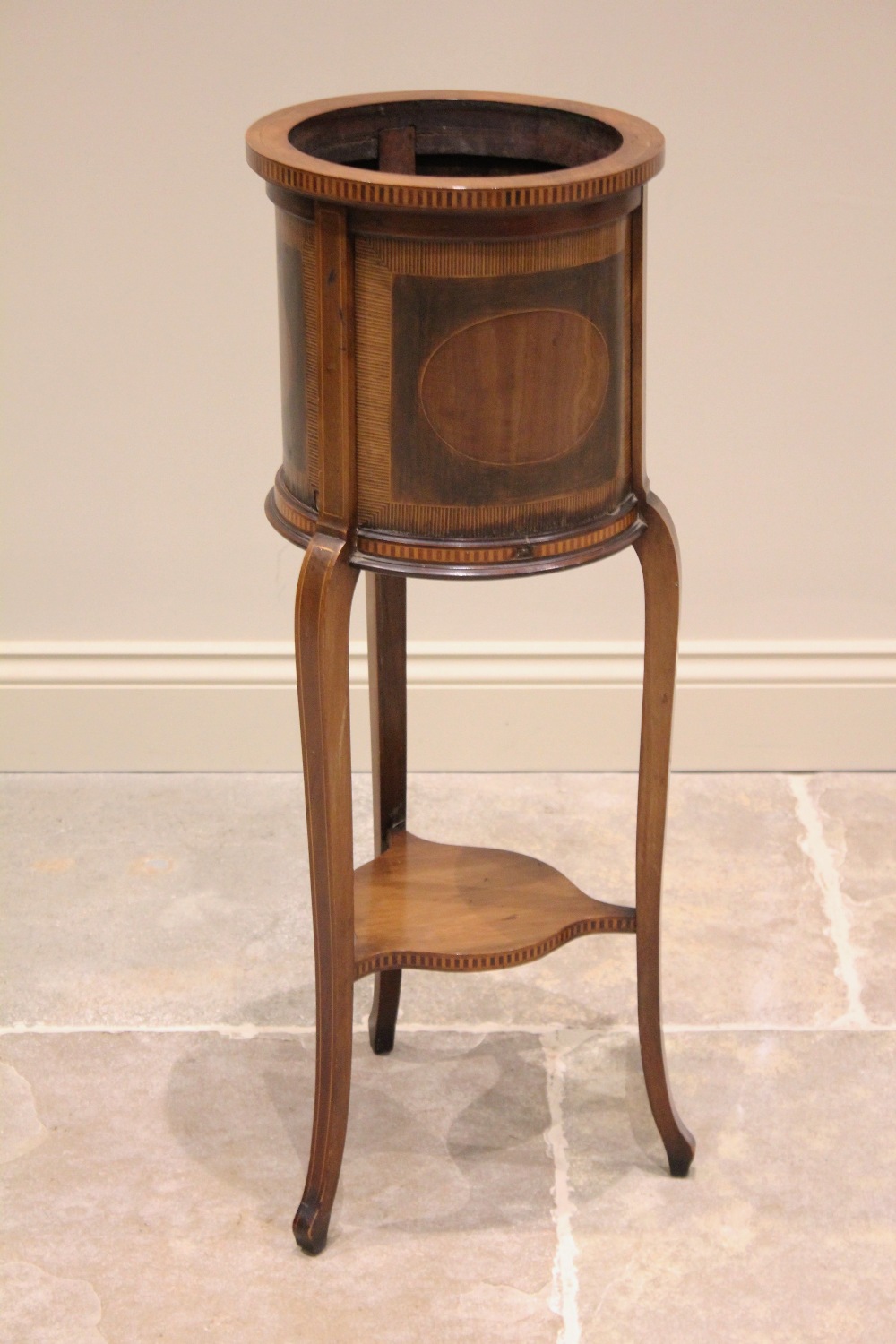 An Edwardian Sheraton revival cylinder jardiniere stand, inlaid with satinwood banding, raised on