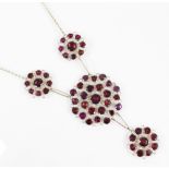 A garnet set drop necklace, the drop designed as two pierced circular panels set with flat cut