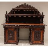 A large and impressive carved Burmese teak pedestal sideboard, the lancet shaped back with two