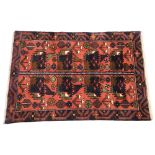 A hand woven wool carpet, with two panels of traditional village design with flowers, foliage and