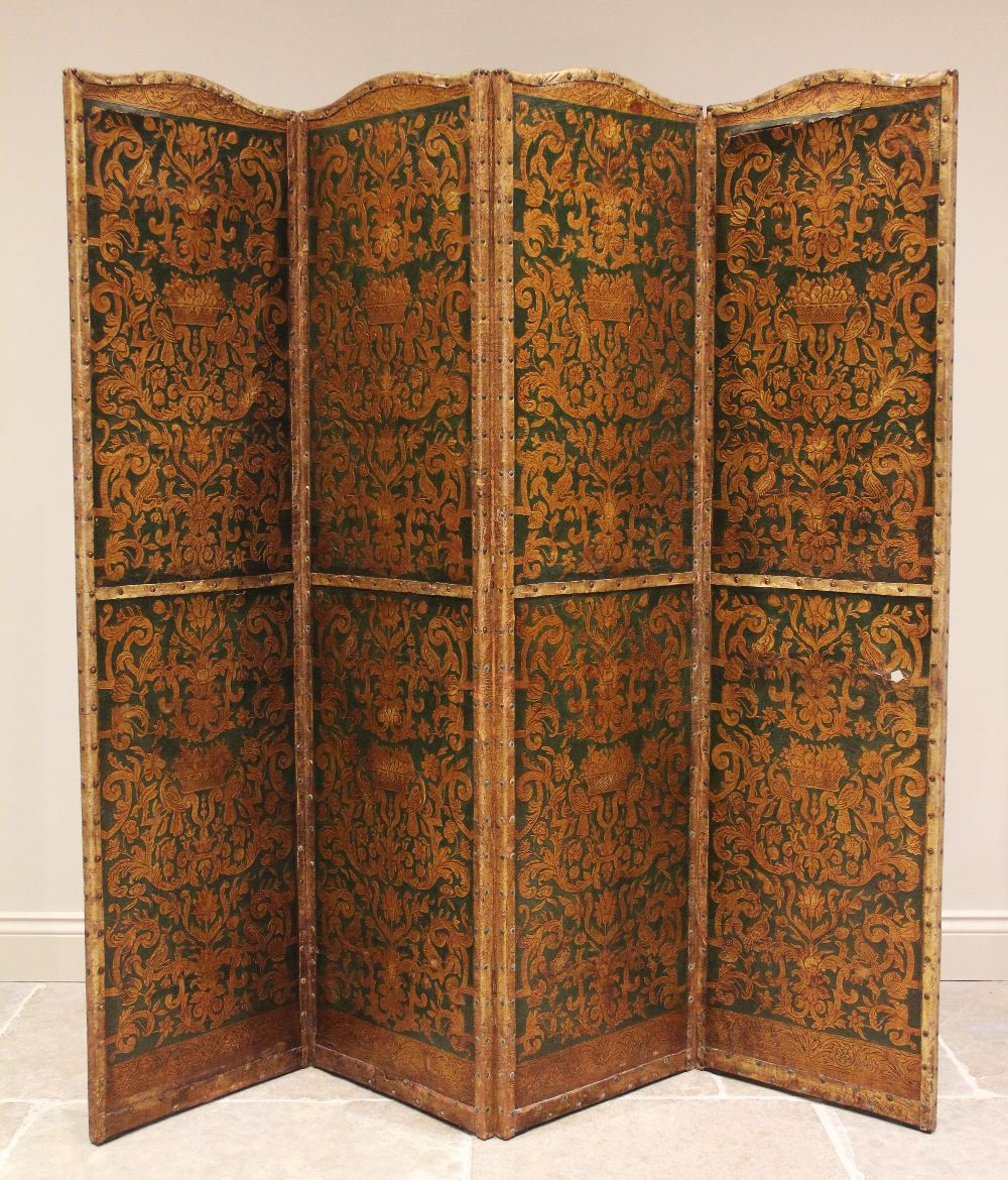 An early 20th century three fold leather room screen, the four panels embossed with a classical