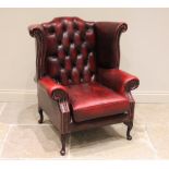 A George II style oxblood red leather wing back fireside armchair, late 20th/early 21st century, the
