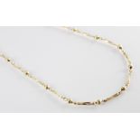 A gold coloured chain, comprising alternating twisted trombone links and textured bead spacers,