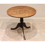 A George III oak tripod table, the circular plank top raised upon a ring turned baluster column,