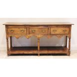 A George III style honey oak dresser base, 20th century, the rectangular twin plank top over three