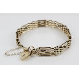 A 9ct bracelet, comprising alternating gate and brick links, length approximately 20cm, suspending a