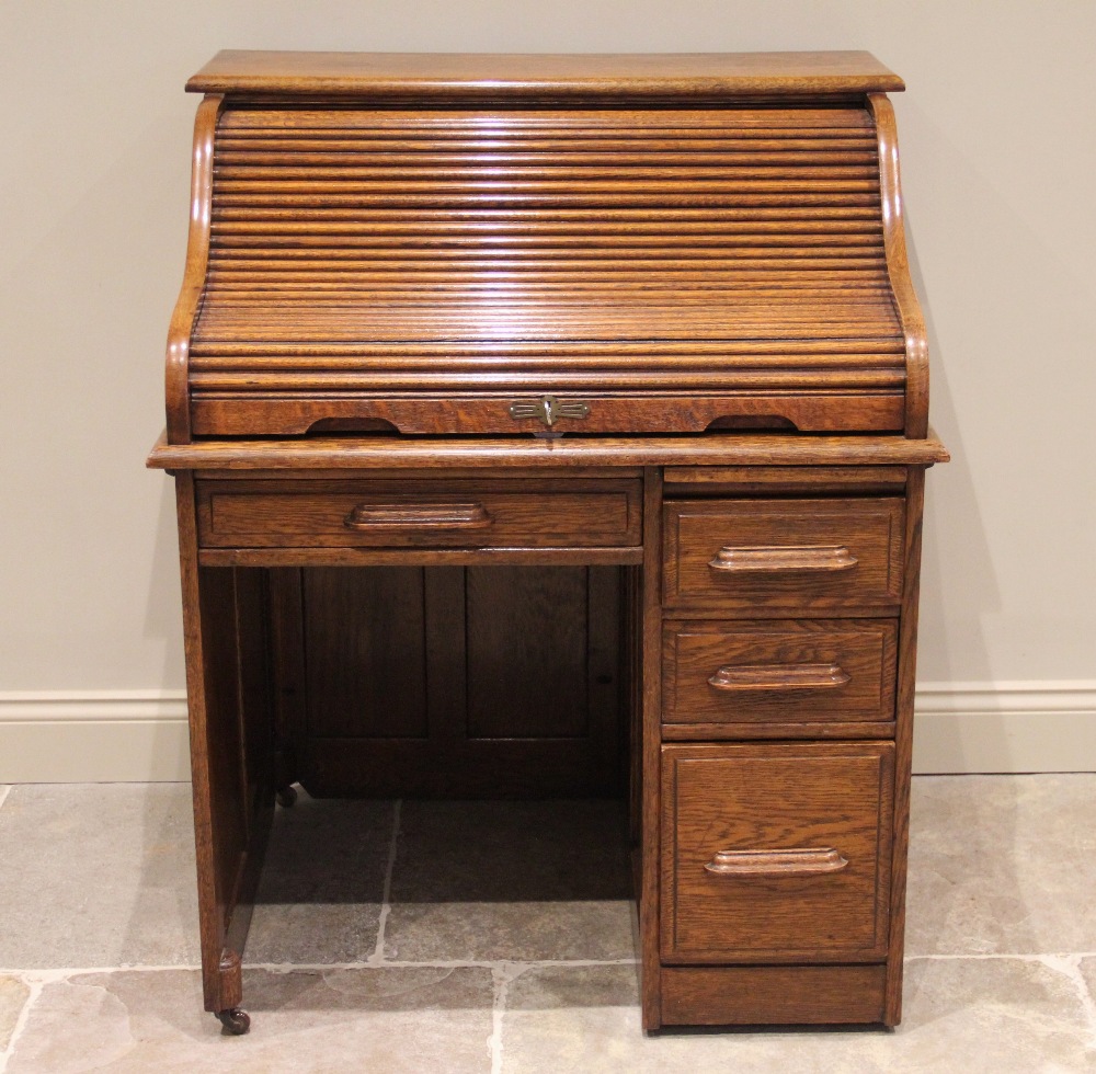 An early 20th century single pedestal oak roll top desk, the tambour sliding front above a single