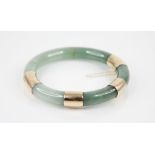 A jade hinged bangle, of plain polished circular form, with 14ct gold mounts, import marks for