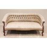 A Victorian walnut framed tub shaped settee, the padded button back extending to carved leaf swept