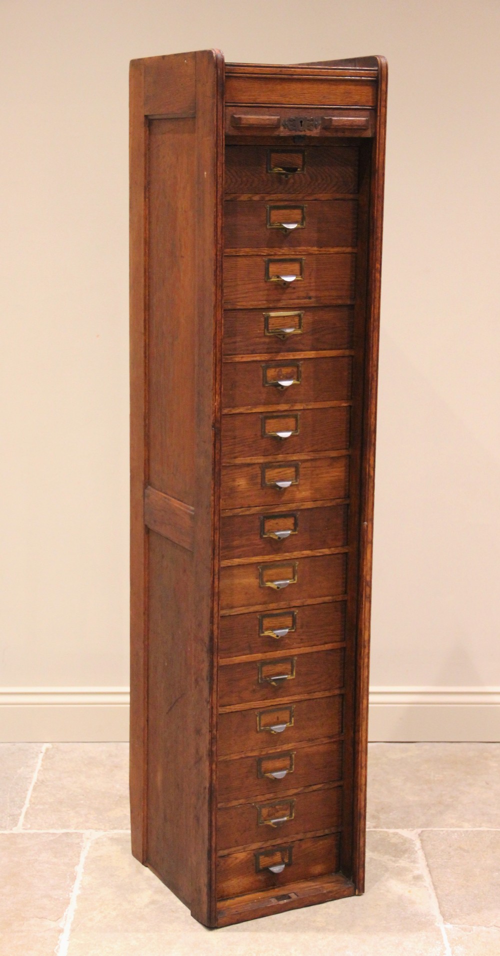 An early 20th century oak tambour front cabinet, of tall rectangular form with panelled sides, the