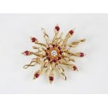 A diamond and ruby set 14ct gold brooch pendant, the twisted sunburst design frame set with