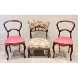 A pair of Victorian rosewood buckle back side chairs, each with a leaf swept rail back above a stuff