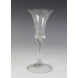 A waisted bell bowl wine glass, the bowl with protruding tiered base on plain stem terminating in