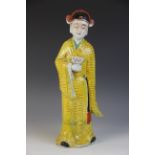 A Chinese porcelain Republic figure, modelled as a figure standing in a yellow robe, holding a