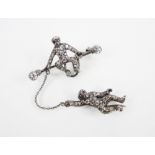 An early 20th century paste set silver coloured monkey brooch, designed as a monkey sat upon a bar