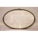 An oval brass wall mirror, the oval mirror plate surrounded by a plain brass frame applied with