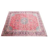 A large Persian hand knotted wool carpet, the central circular foliate medallion upon a red ground