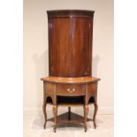 A George III freestanding mahogany bowfront corner cupboard, with a dentil cornice above a pair of