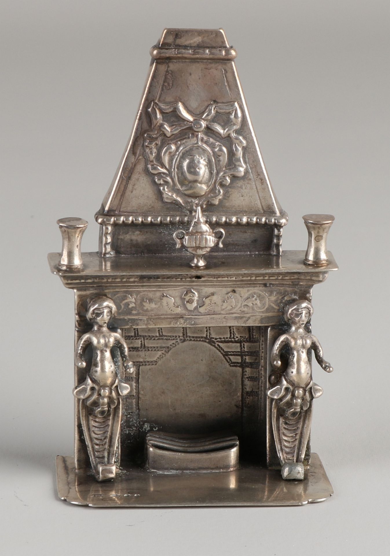 Silberner Miniaturkamin, 835/000, verziert mit Figuren, Vasen und Medaillon. Auf einer rechteckige