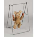 Antique teddy bear on swing, 1920