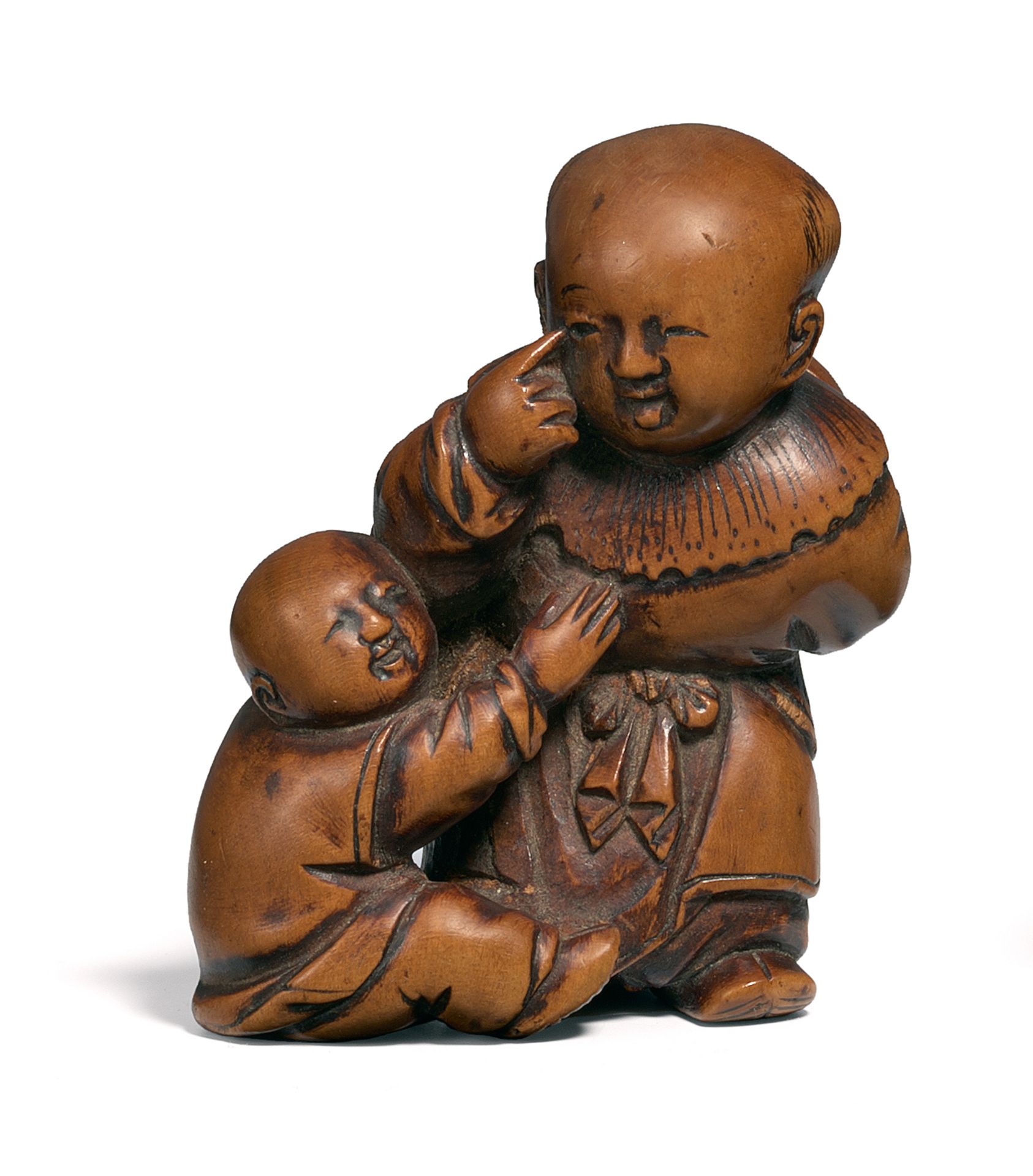 NETSUKE: TWO KARAKO DOING BEKANKO. Japan. Edo period. 19th c. Boxwood. A boy hiding an Okame mask