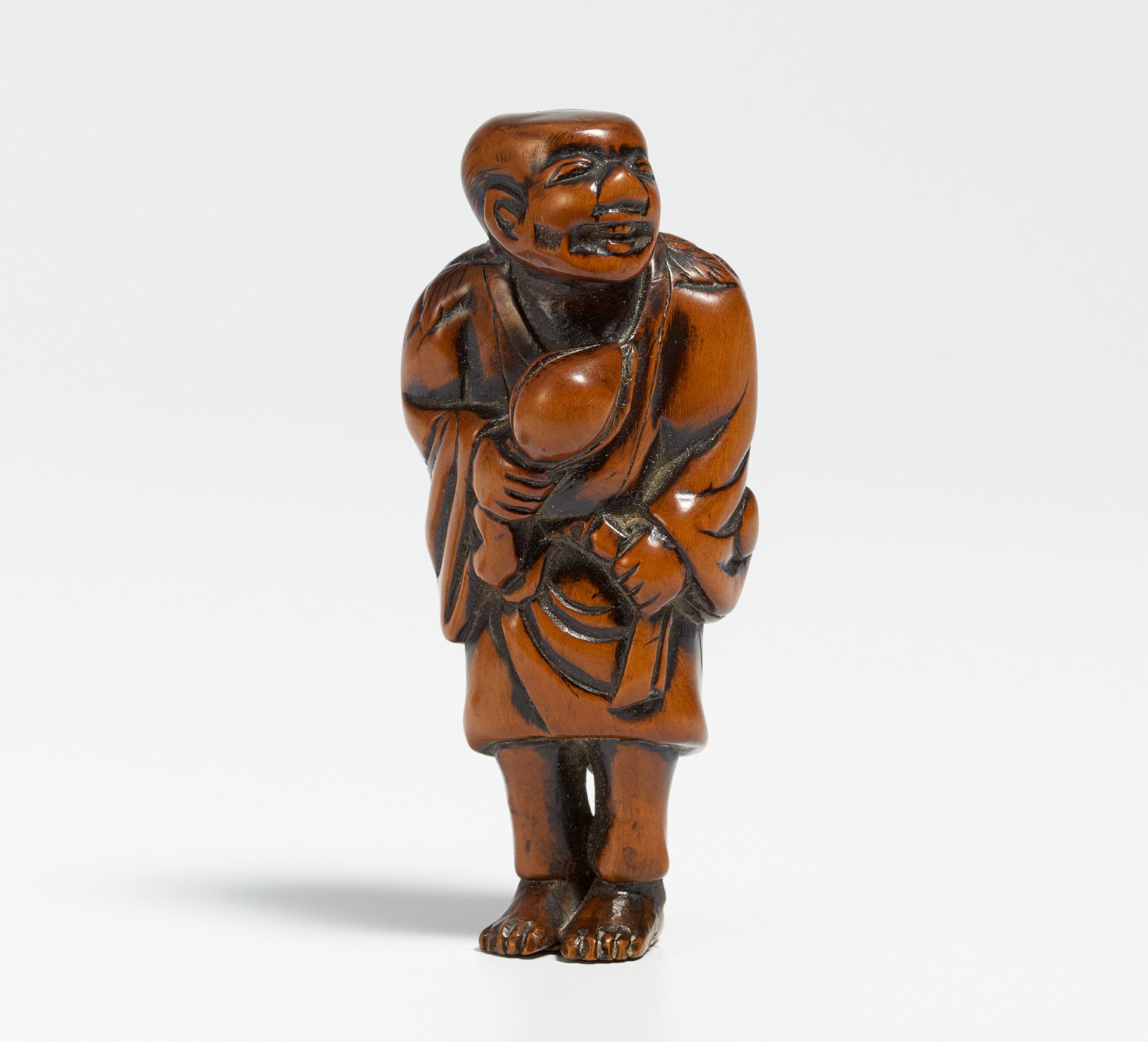 NETSUKE: STANDING TOBOSAKU (DONGFANG SHUO) WITH PEACH AND LEAF COLLAR. Japan. 19th c. Boxwood,