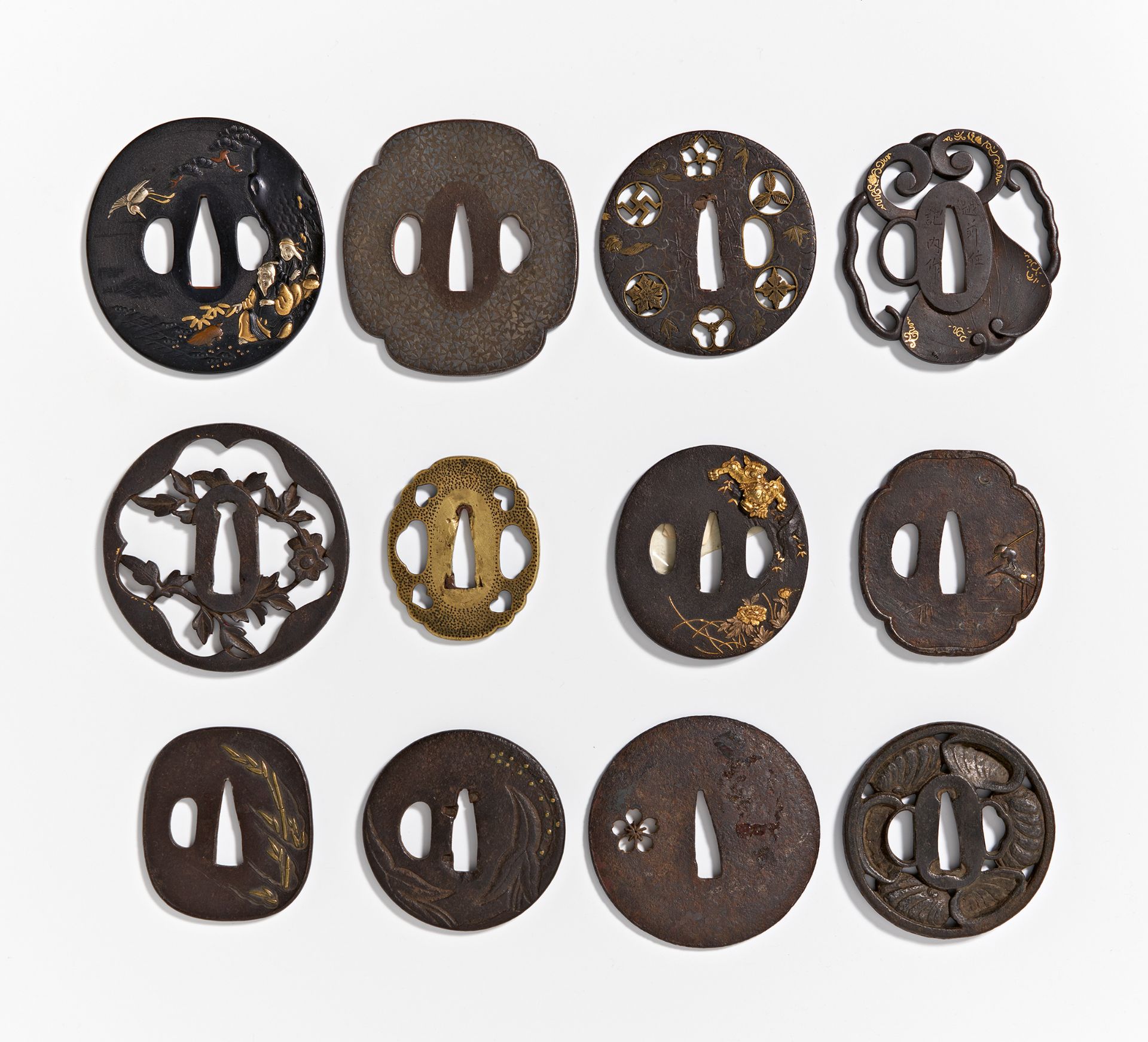 TWELVE TSUBA. Japan. 18th-19th c. and earlier. Two in bronze, ten from iron. Partly with inlay and