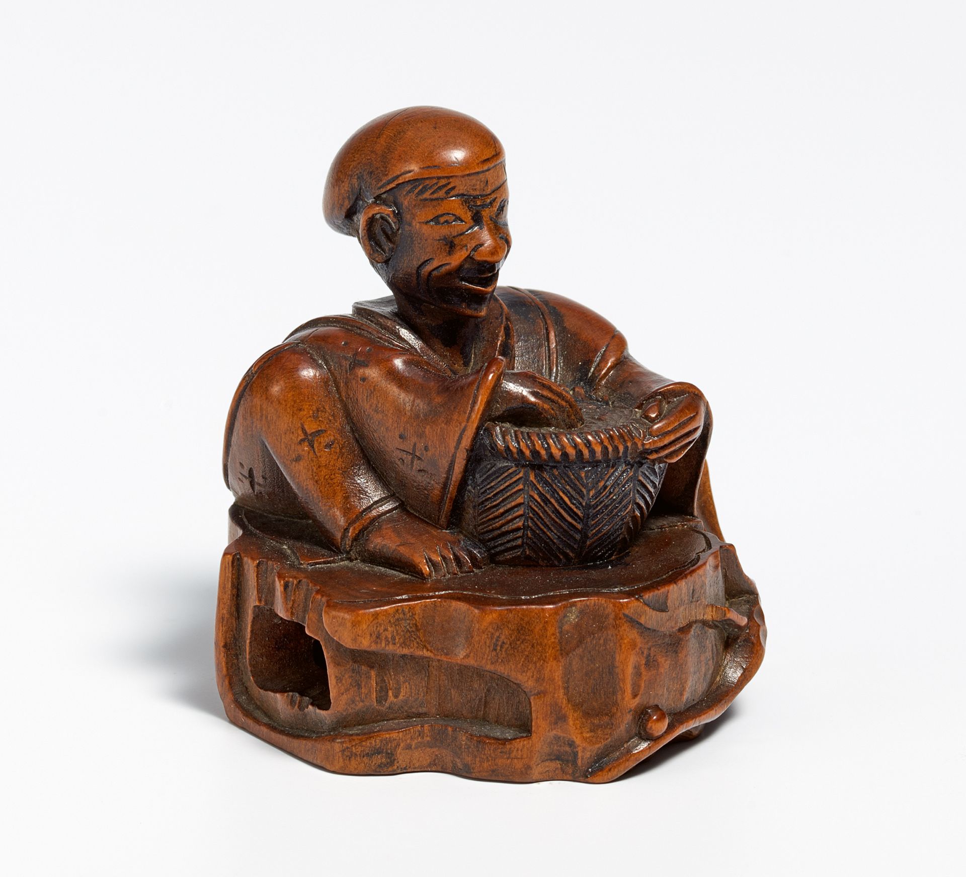 NETSUKE OF HANASAKA JIJII WITH ASH BASKET SITTING ON THE STUMP OF A CHERRY TREE. Japan. 19th c.