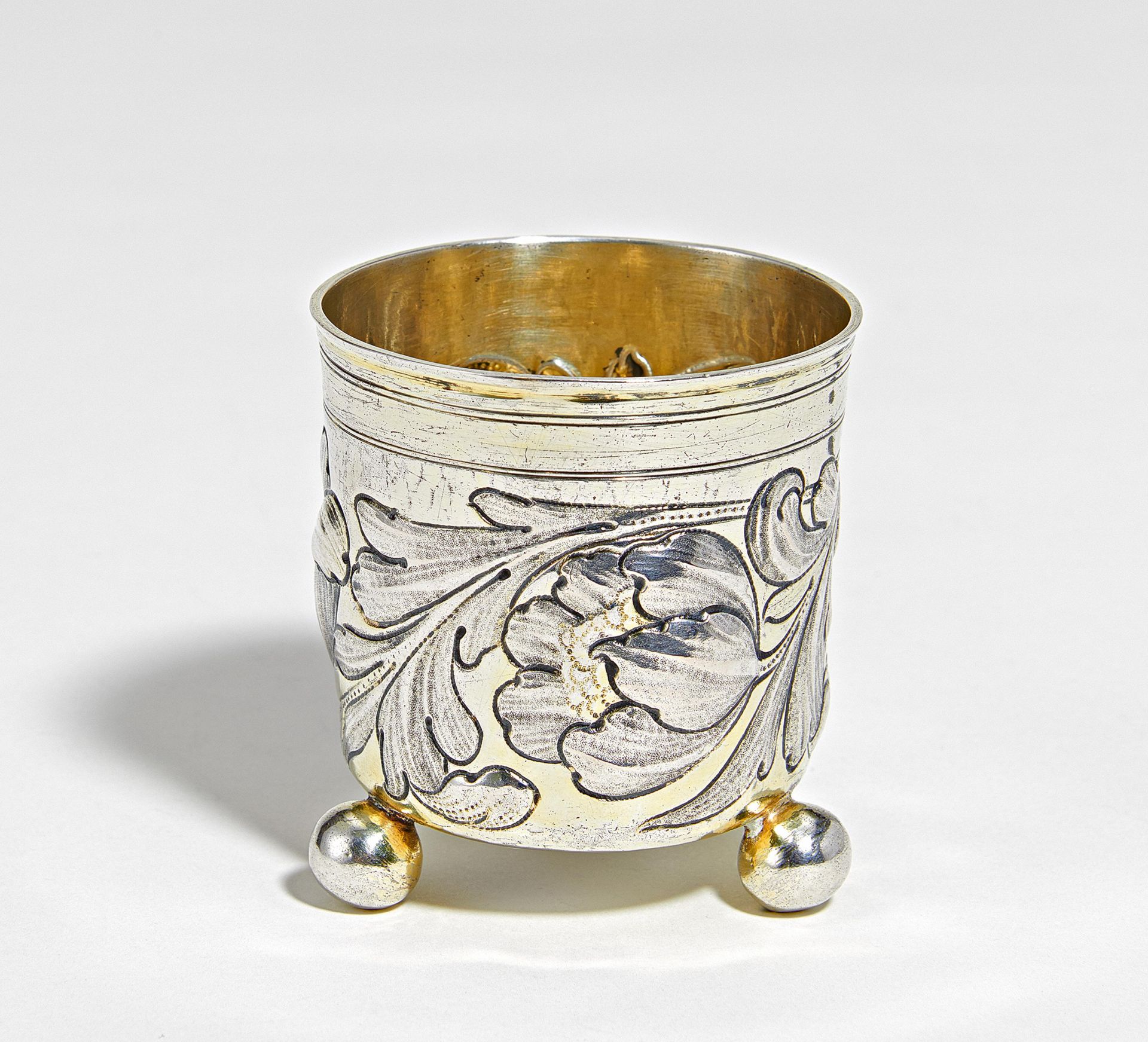 Small silver beaker with spheric feet and flower tendrils