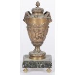 A cast bronze lidded urn on a black marble base.