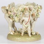 A porcelain coupe supported by (3) putti and decorated with roses, 20th century.