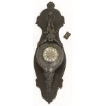 A cast iron longcase clock in the shape of a bellows, mounted on a wooden carving, late 20th century