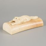 An ivory presse-papier with carved reclining dog, 1st half 20th century.