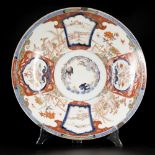 A large Imari dish with floral decoration and landscapes on the outside. Japan, 19th century.