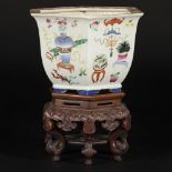 A porcelain cachepot florally decorated with antiques on a wooden base, China, 20th century.