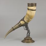 A drinking horn made of an ox horn, carried by a putto, ca. 1920.