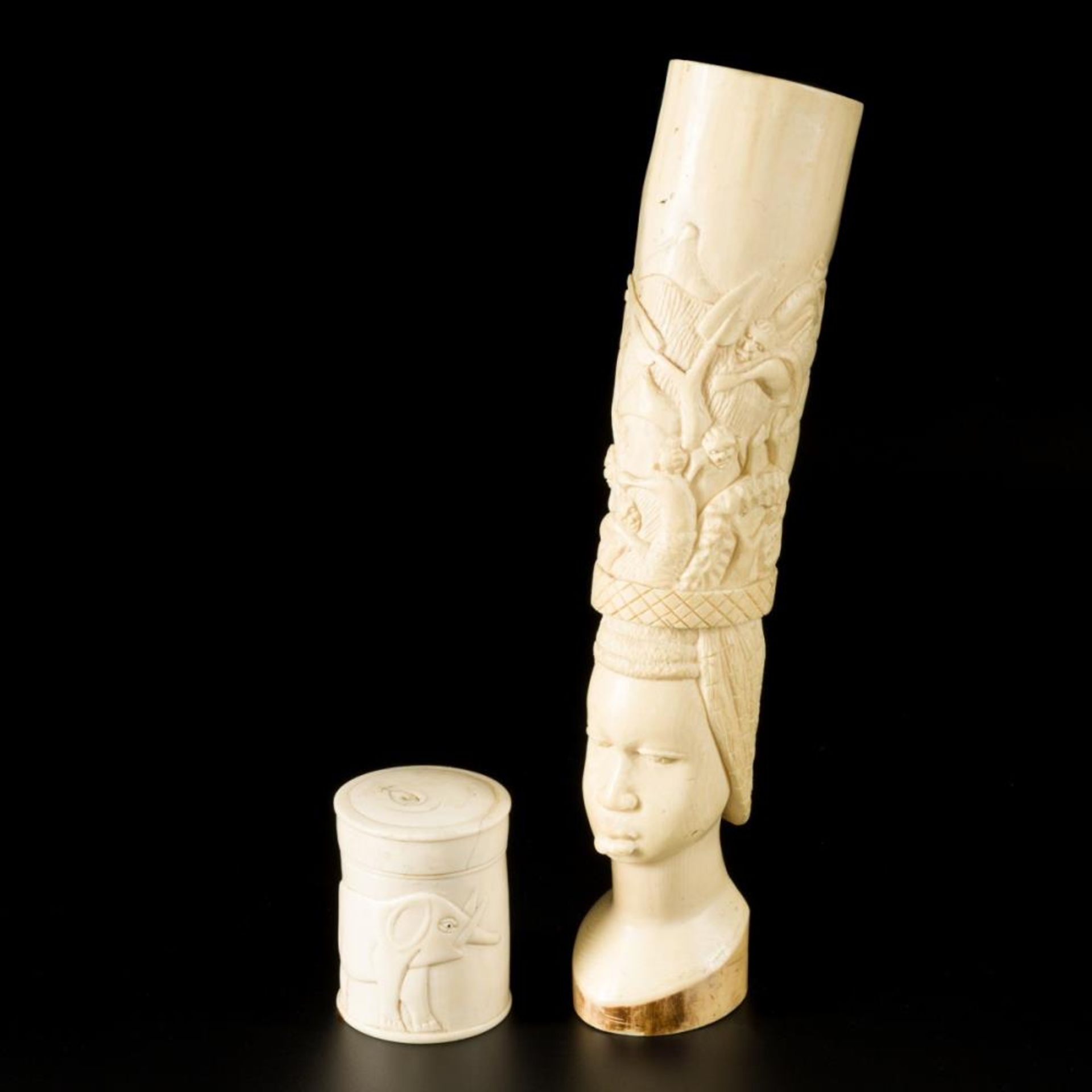 two ivory carvings of a villagescene above a wokmans head, and a lidded pot decorated with elephants