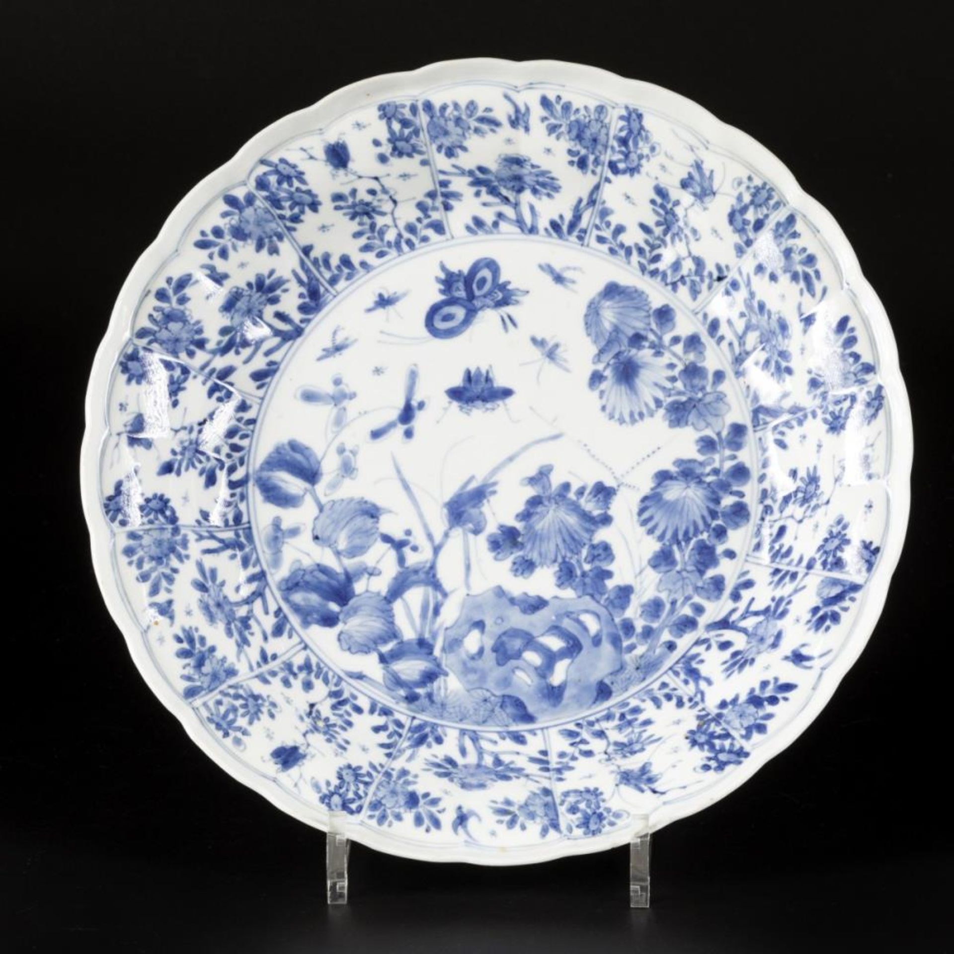 A porcelain charger with floral decoration in sections, with a central decoration of insects and flo