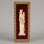 An ivory relief of a standing Madonna with lily mount on red velvet background, ca. 1900.