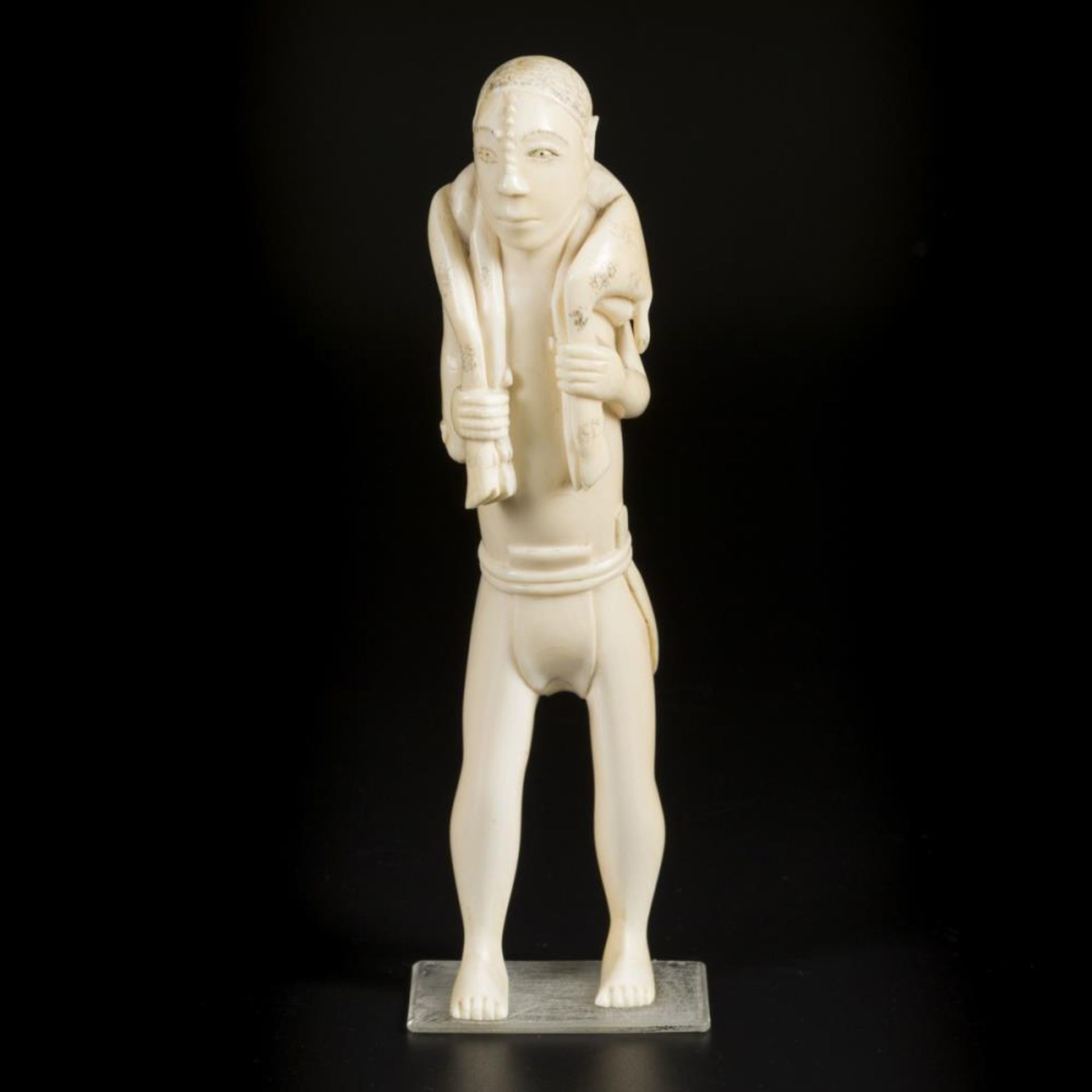 An ivory carving depicting a hunter with antilope on his shoulders, D.R. Congo, ca. 1900.