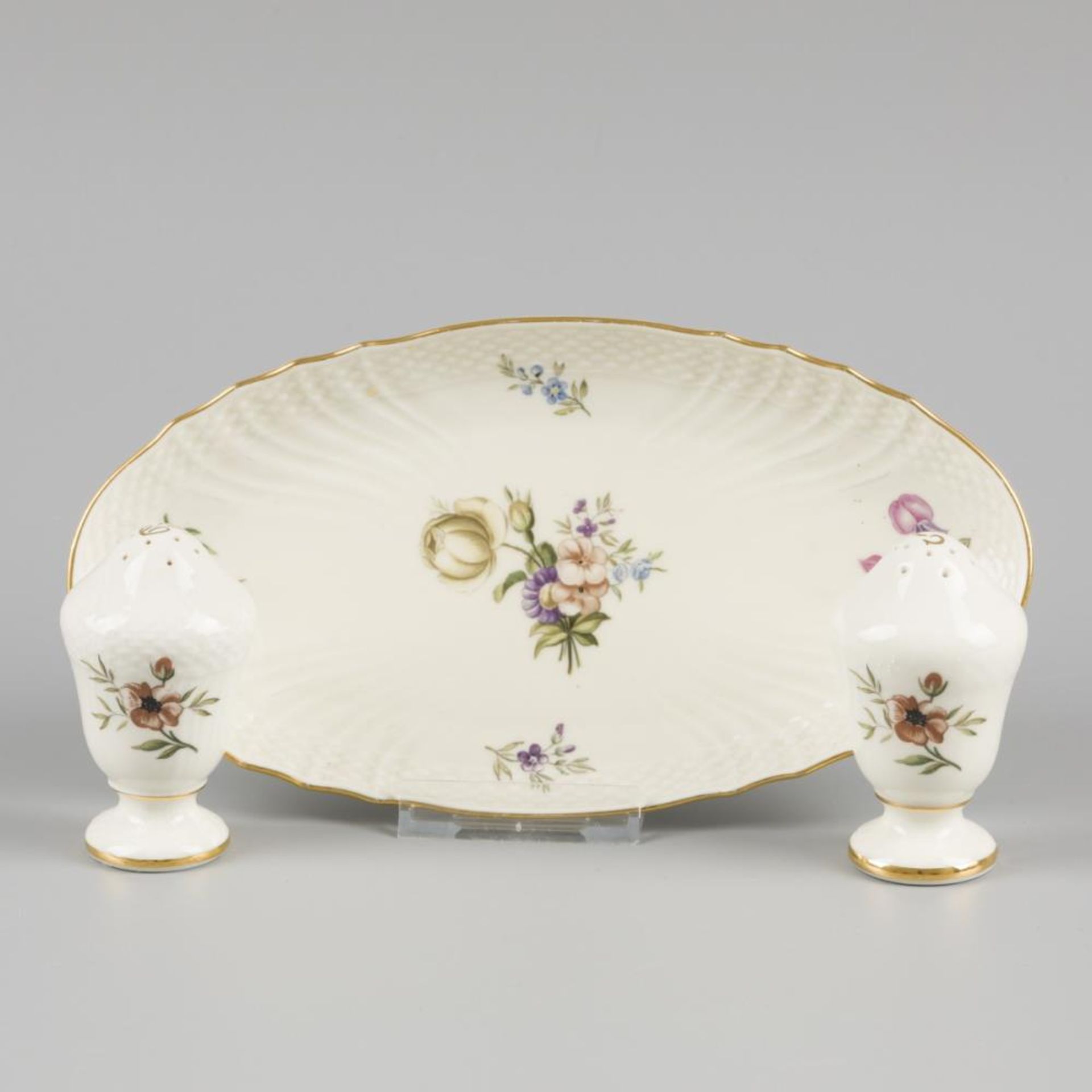 A porcelain salt and pepper shakers with a saucer decorated with flowers, marked Royal Copenhagen. D
