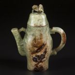 A Celadon jade teapot decorated with a lion as lid knob and relief decoration of a bird and prunus.