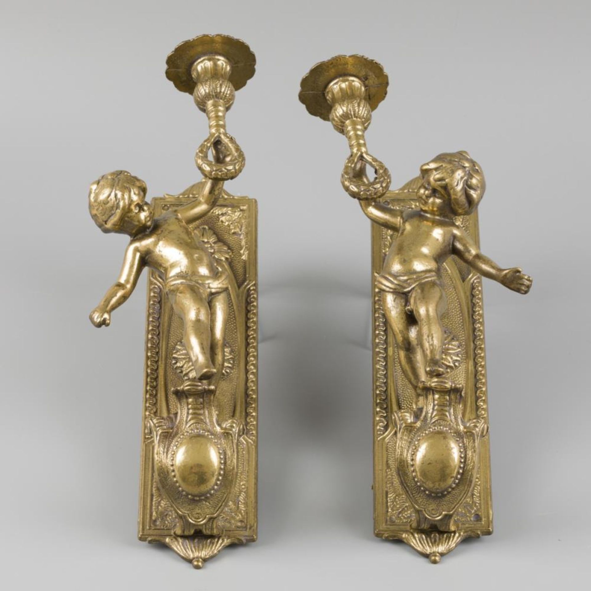 A lot comprising (2) candlestick holders, adorned with putto holding a candleholder, 20th century.