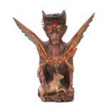 A polychrome wooden sculpture, 'Singa' with protruding tongue and spread wings, holding down a