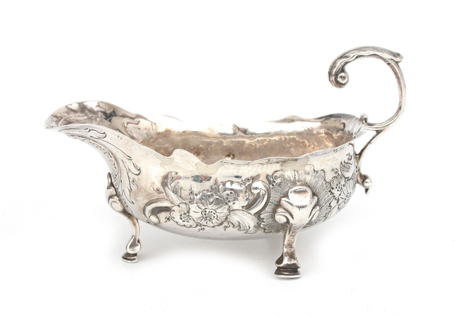 An 925 silver gravy boat on three feet with embossed- and engraved floral decoration, Robert Brown,