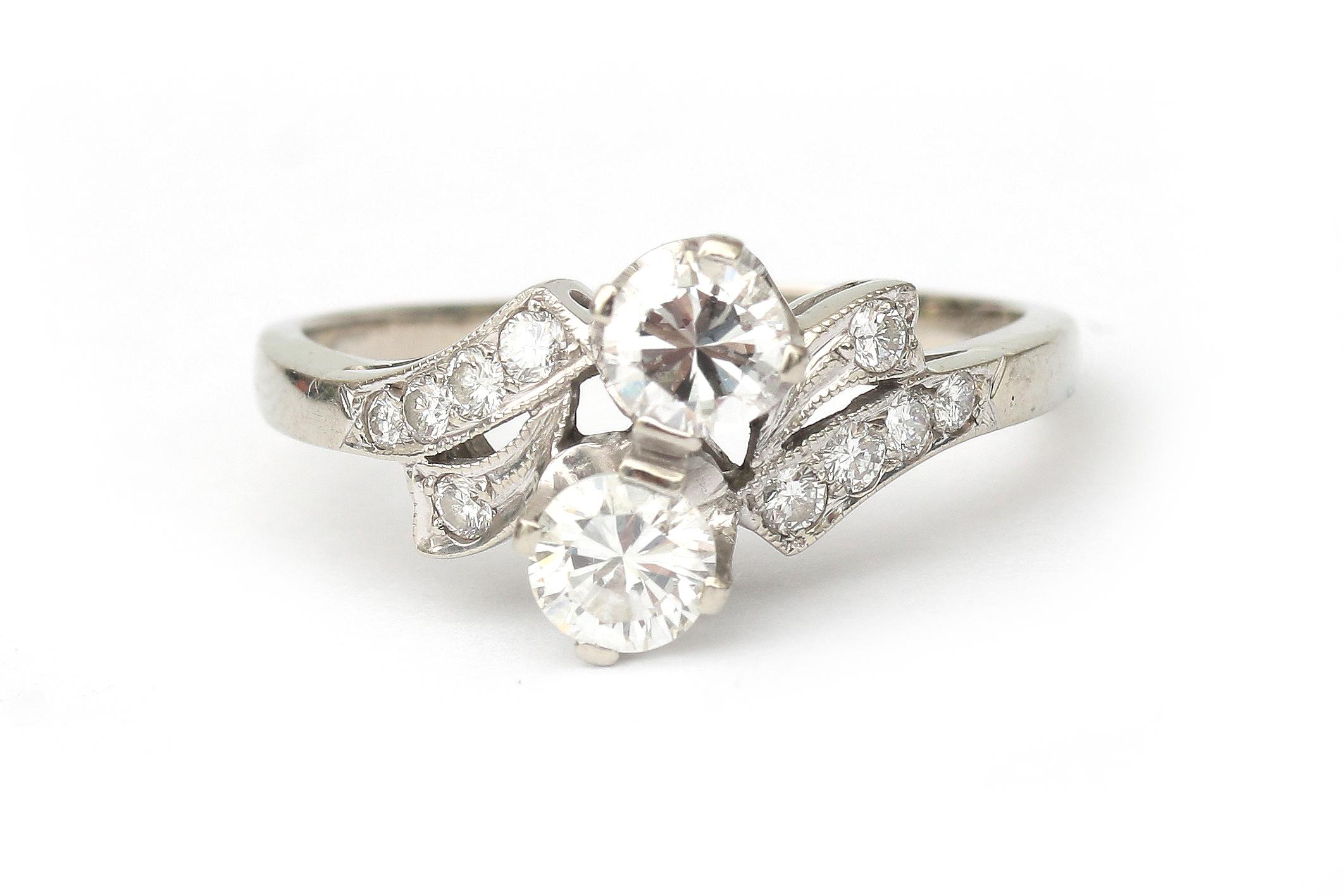 A 14 karat white gold diamond cross over ring