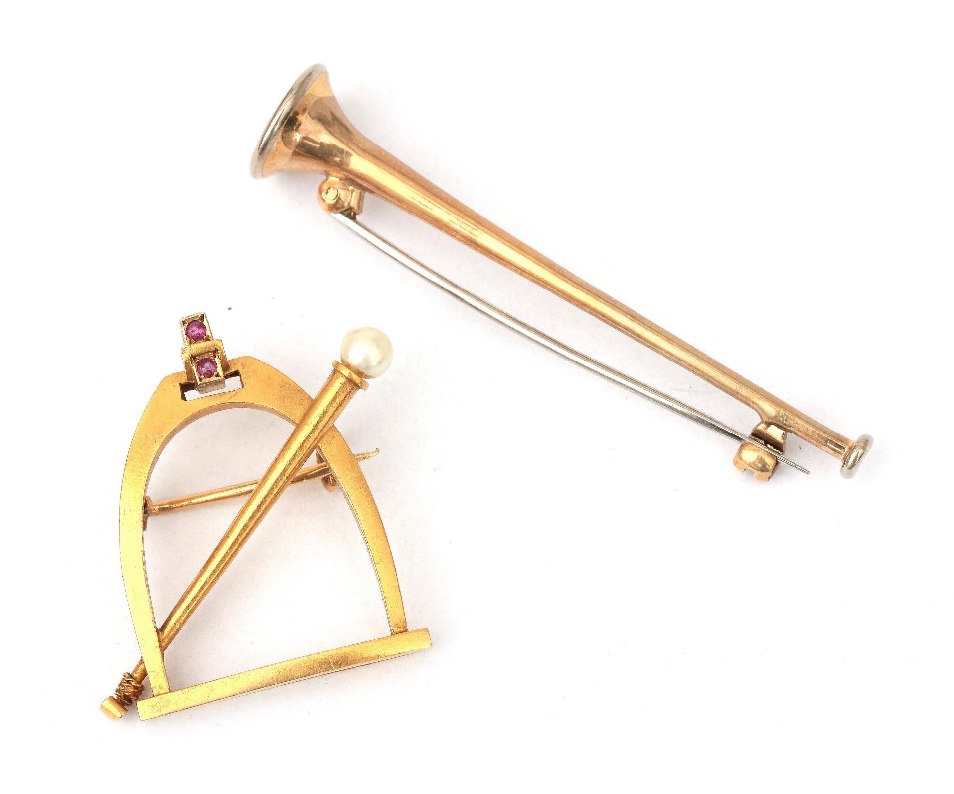 Two gold brooches in het shape of a stirrup and a trumpet
