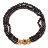 A three strand garnet necklace to a 14 karat gold clasp